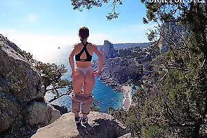 Public erotica, a girl with a stunning figure shows her magnificent ass against the backdrop of the sea and mountains. DickForStepSister